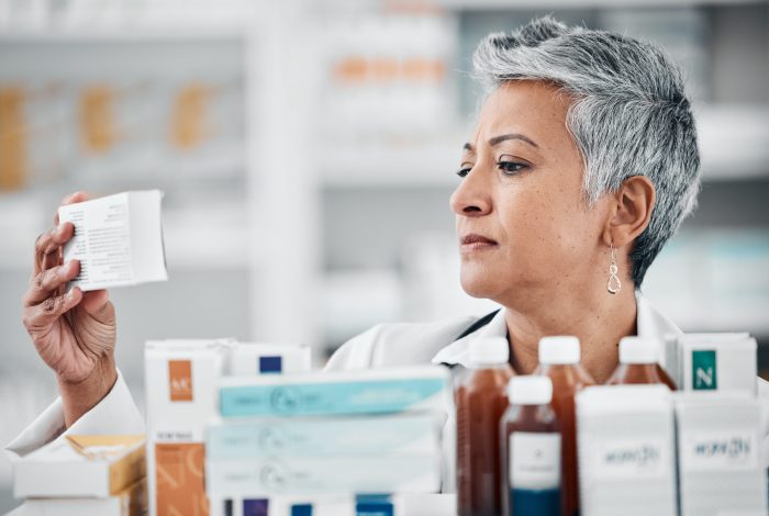 FDA Related services Pharmacy, stock and senior woman pharmacist with box, pills and medication, reading and checking in.