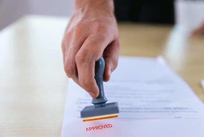 Business Man Stamping With Approved Stamp On Document. Business Man Stamping With Approved Stamp On Document. Business approve Stamp and certificate concept. Businessman Hands Stamping a document