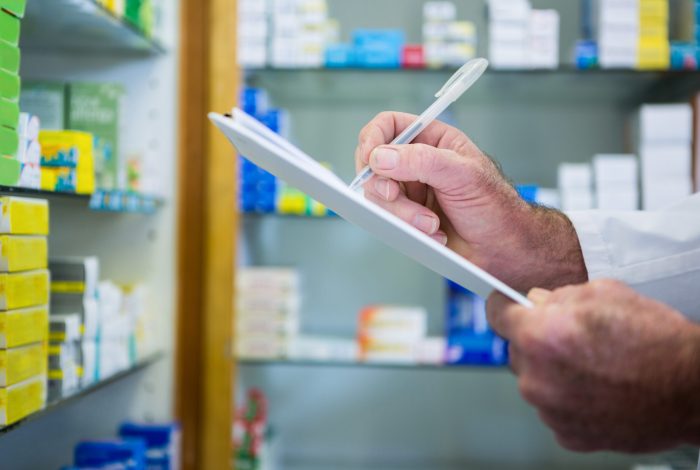Pharmacist writing on clipboard in pharmacy Pharmacist writing on clipboard in pharmacy