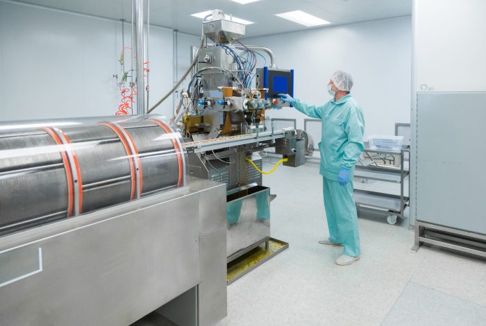 Pharmacy industry factory man worker in protective clothing in sterile working conditions Pharmaceutical technician in sterile environment working with equipment at pharmacy industry