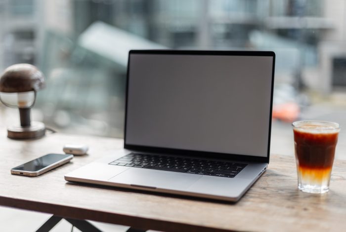 Wooden office desk with laptop, smartphone and headphones with a Wooden office desk with laptop, smartphone and headphones with aromatic espresso tonic coffee on urban background. Remote work and freelance. Mockup laptop with free copy space. Workspace